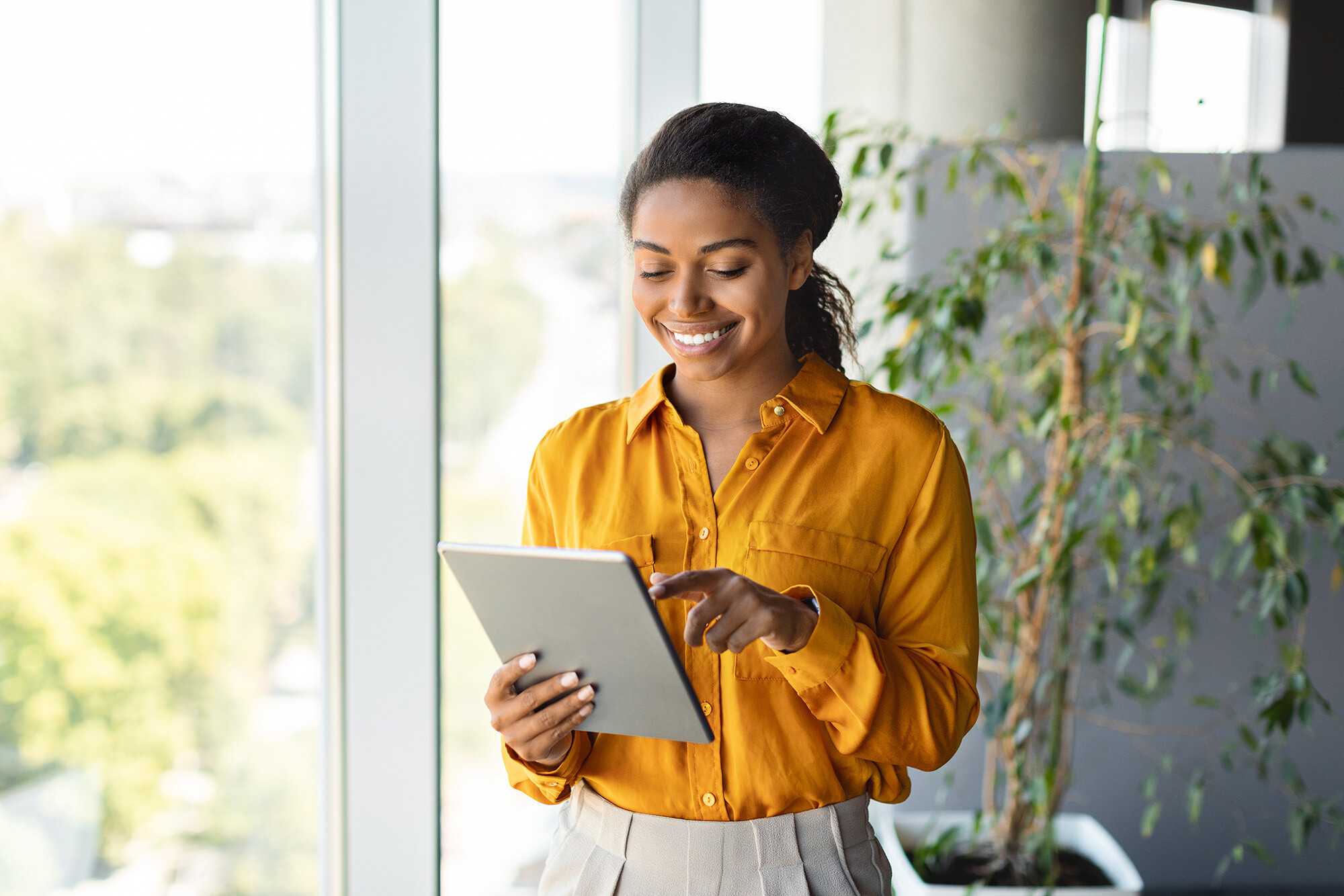 Happy african american woman dressed professionally reading a tablet in an office building